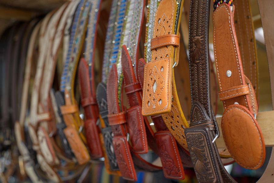 Hand-tooled leather belts hanging in a row