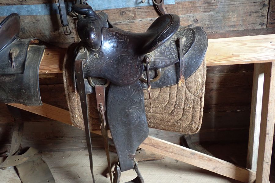 A tooled leather western saddle in a wooden barn